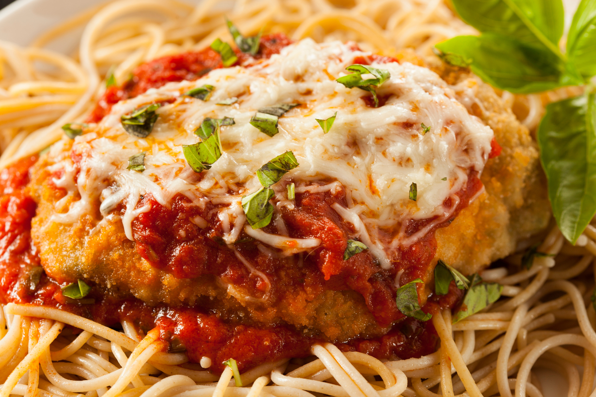 Garlic parmesan chicken pasta with cherry tomatoes and basil leaves.