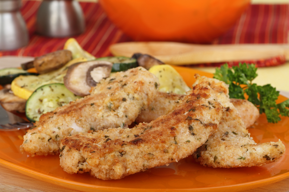 Golden brown chicken tenderloins on a white plate